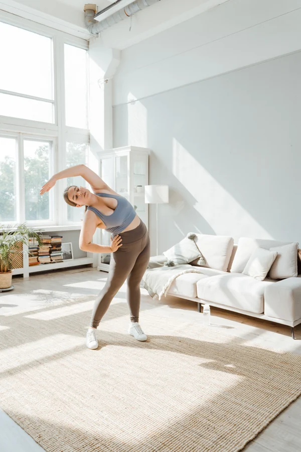 Woman stretching beside a sofa at home